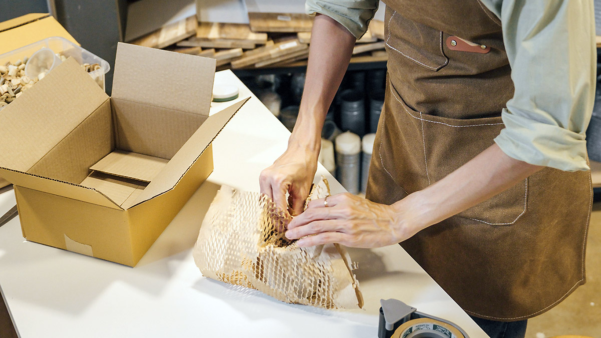 Mann verpackt Ware in braune Wabenpapierpackung ein