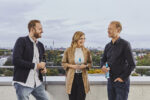 3 people standing on the terrasse drinking water overlooking Hamburg.