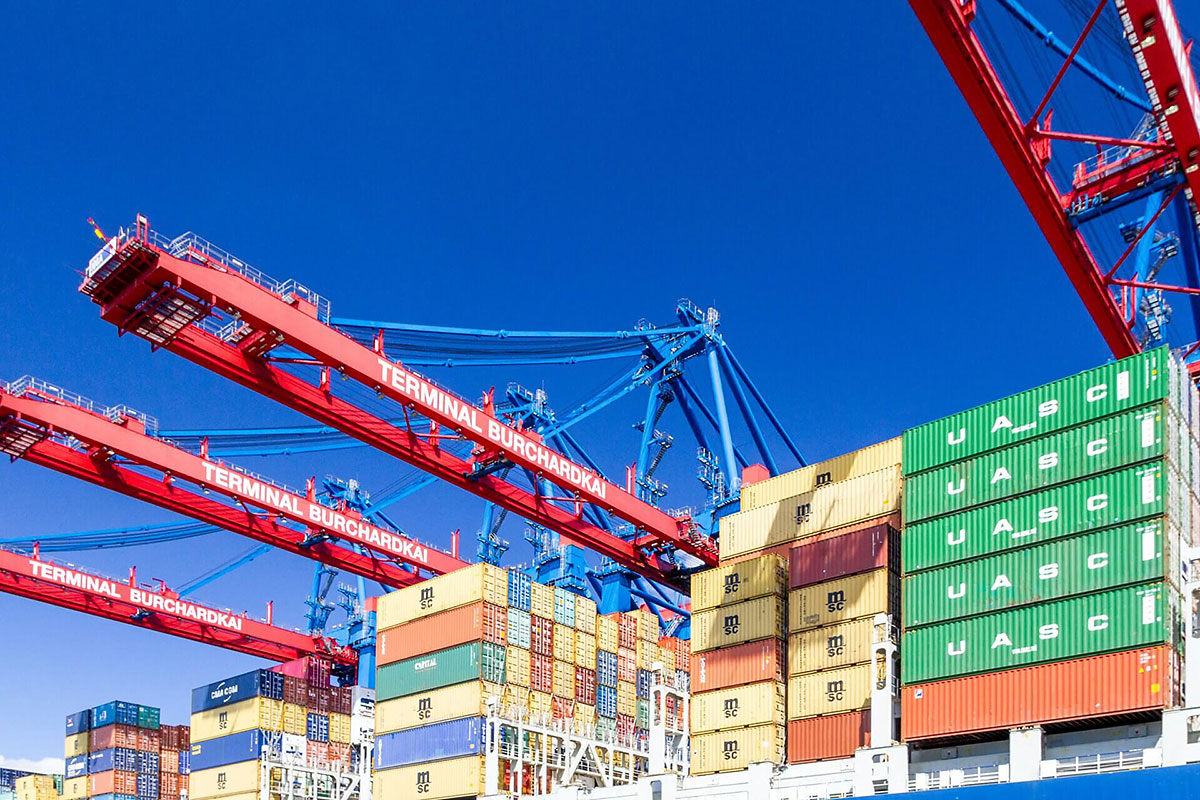 Harbour with cranes and piled containers.