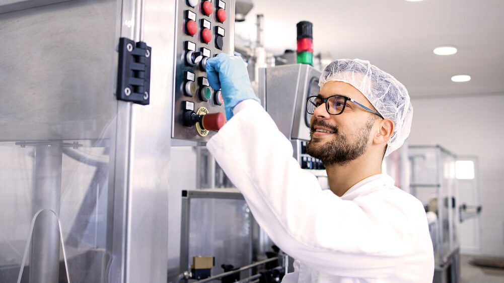 Mann arbeitet an einer Maschine in einem Reinraum