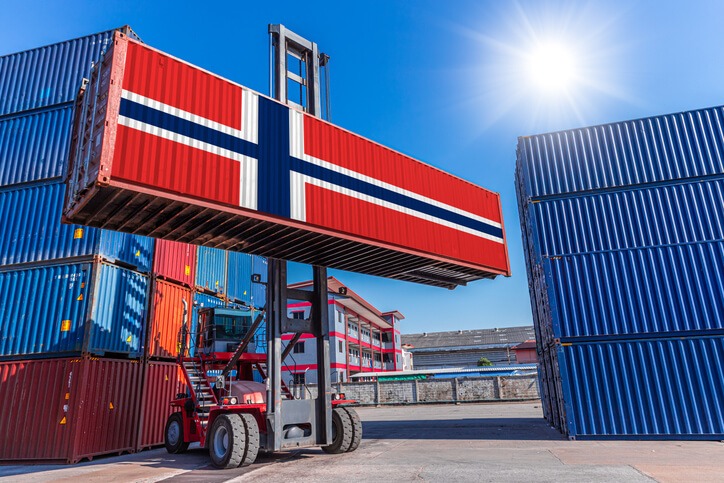 Importaciones de Noruega: La imagen muestra una grúa de apilamiento que transporta un contenedor con bandera noruega.